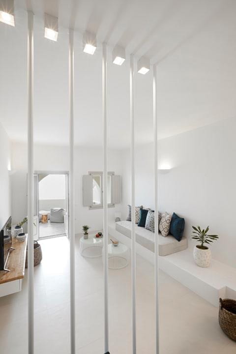 Living area viewed through slender white room-divider rods with a built-in cushioned bench