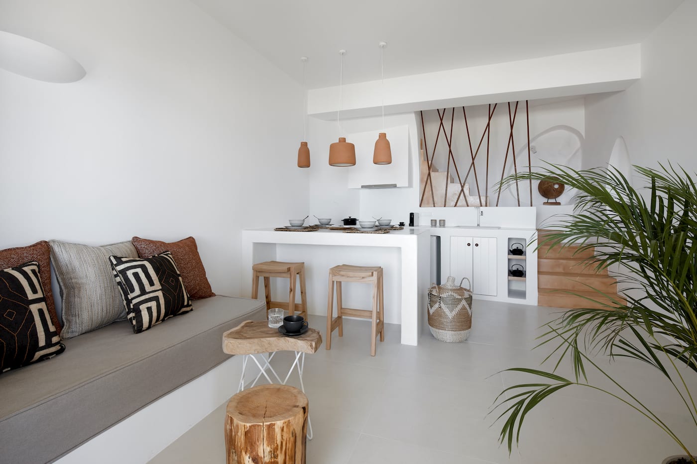Compact kitchenette with a white counter, wooden bar stools and a cushioned bench seat