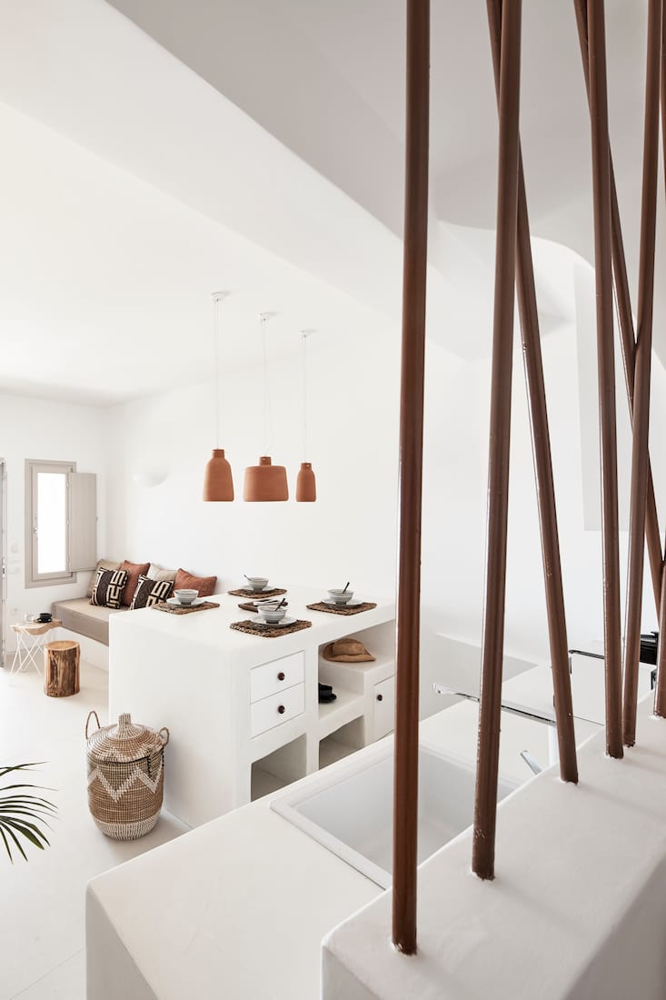 Living space viewed through a timber-pole balustrade, showing the dining counter and cushioned seating below