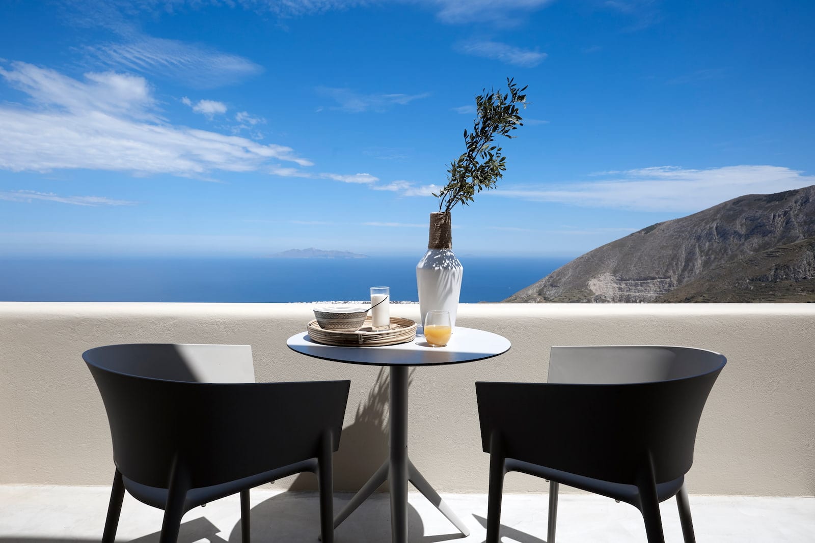 Suite One terrace table for two overlooking the Aegean Sea and Santorini's rugged mountains
